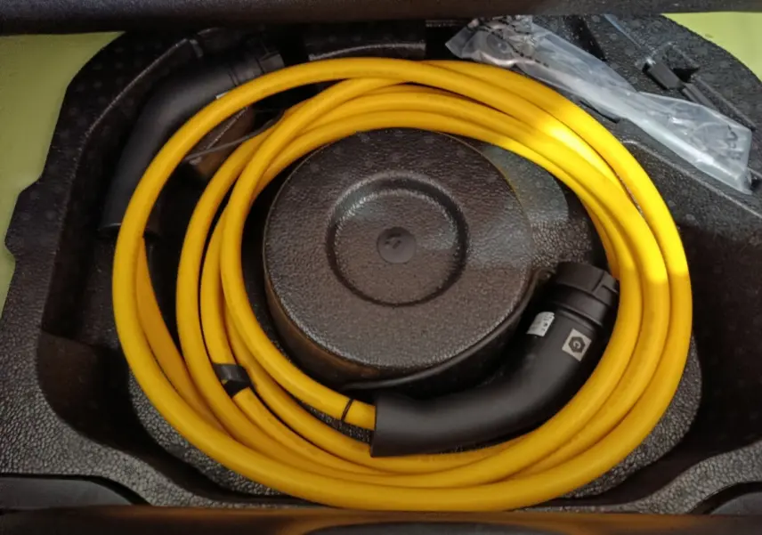 Câble de recharge jaune enroulé dans le coffre d'une Fiat 500 BEV 24kWh électrique, vue de dessus.