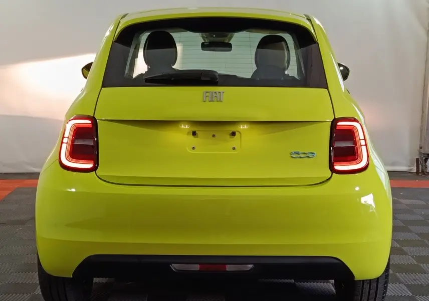 Vue arrière d'une FIAT 500 BEV 24KWH jaune vif, avec feux arrière LED allumés et logo distinctif visible.