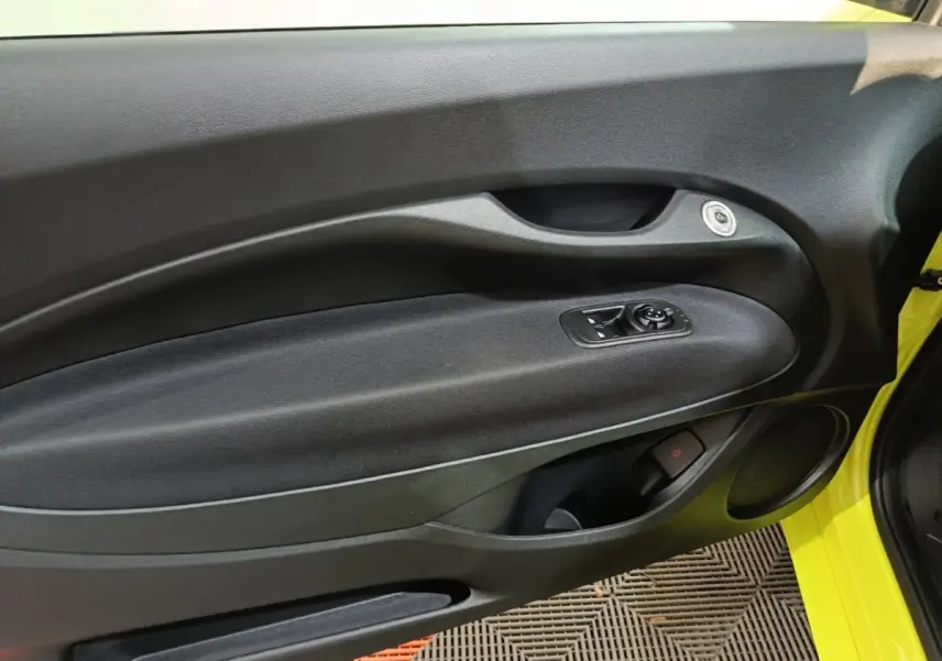 Vue intérieure côté gauche de la porte d’une FIAT 500 BEV 24KWH jaune avec commandes de vitres et haut-parleur intégré.