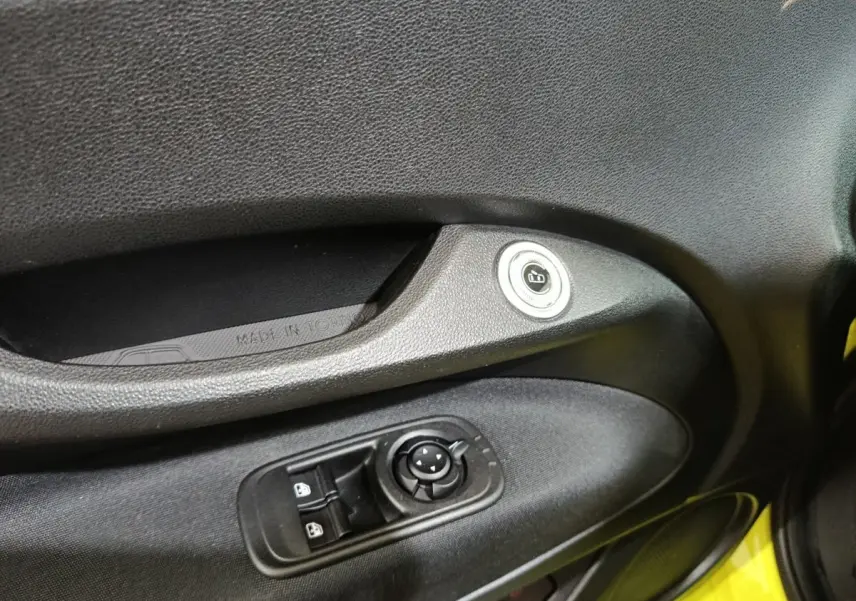 Détail de la porte côté conducteur du FIAT 500 BEV jaune 2024 avec commandes de vitres et bouton de verrouillage.