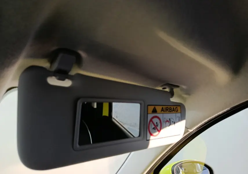 Détail du pare-soleil côté conducteur avec miroir intégré, reflet du rétroviseur et carrosserie jaune vif visible.