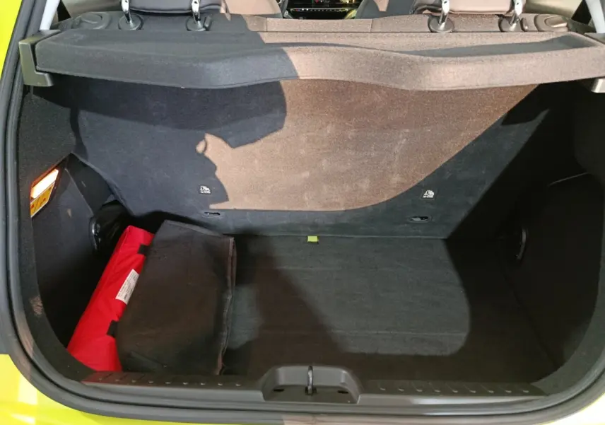Coffre ouvert vu de l'arrière d'une FIAT 500 BEV 24KWH jaune, avec banquette arrière et trousse de secours rouge visible.