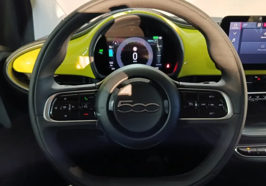 Vue rapprochée du volant cuir synthétique noir du Fiat 500 BEV 24KWH 2024 avec tableau de bord jaune et écran numérique.