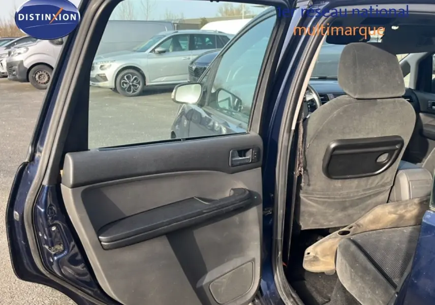 Vue intérieure côté gauche arrière d'une Ford C-MAX bleu foncé métal de 2005 avec porte ouverte et sièges en tissu gris.