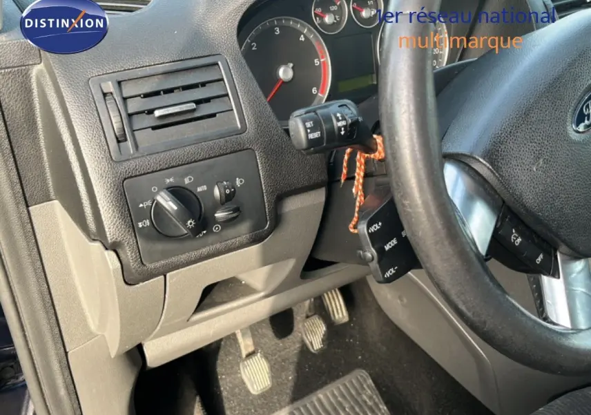 Vue intérieure côté conducteur du tableau de bord et pédales d'une Ford C-MAX 1.6 TDCI 110CH Ghia de 2005, volant noir.