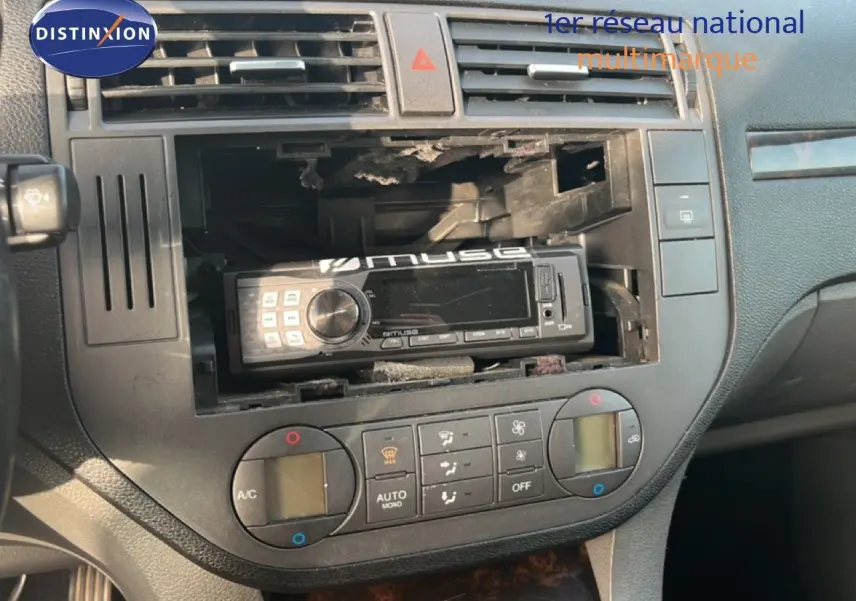 Vue rapprochée du tableau de bord noir d'une Ford C-MAX 2005, avec autoradio Muse installé et commandes de climatisation visibles.