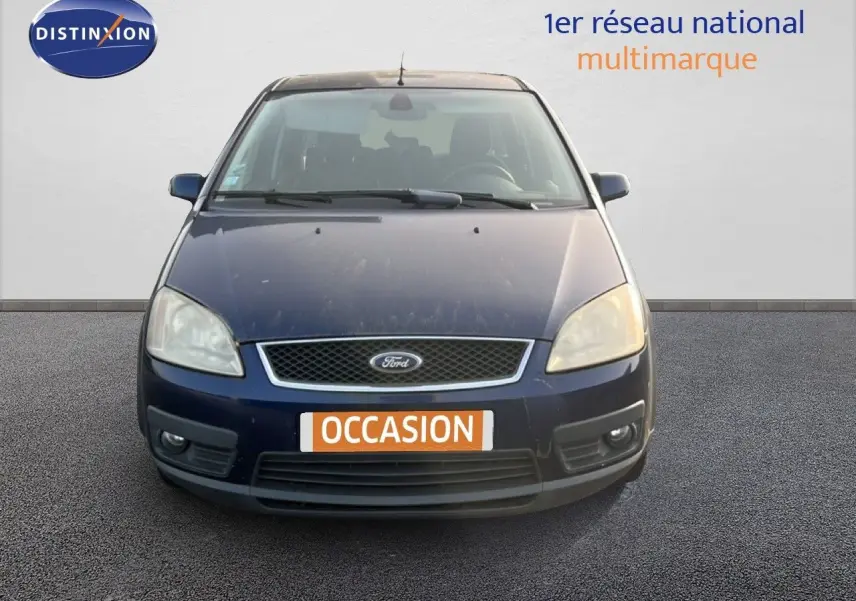 Vue frontale d'une Ford C-MAX 2005 bleu foncé métal avec plaque "OCCASION" et phares légèrement ternis.