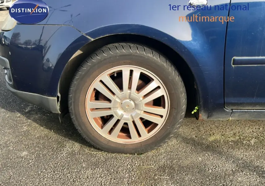 Gros plan sur la roue avant gauche d'une Ford C-MAX bleu foncé métal de 2005, avec jante en alliage et carrosserie légèrement usée.
