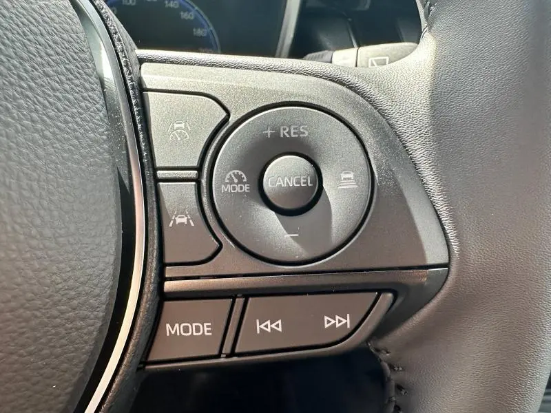 Gros plan sur les commandes du volant côté droit d'une Toyota Corolla noire 2025 avec régulateur adaptatif et mode audio.