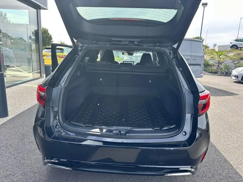 Coffre ouvert vu de l'arrière d'une Toyota Corolla noire 2025, montrant l'espace de chargement vide et les feux arrière LED.