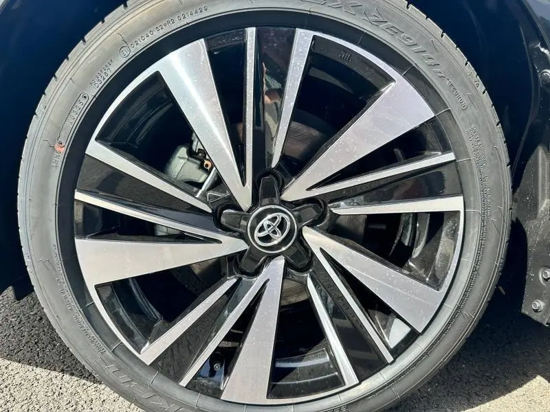 Gros plan sur la jante alu noire et argentée de la Toyota Corolla 2025 hybride, avec logo Toyota central visible.