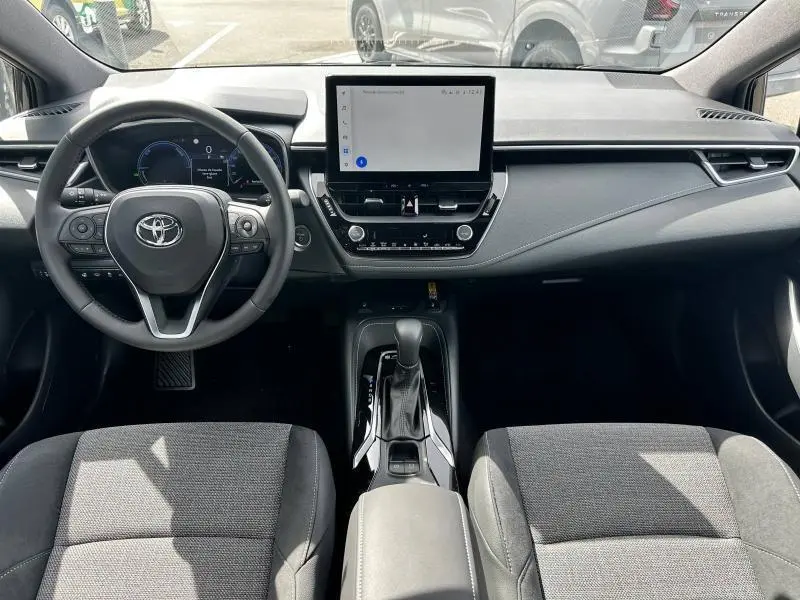 Intérieur avant de la Toyota Corolla 1.8 Hybrid noir, tableau de bord moderne avec écran tactile central et volant multifonction.