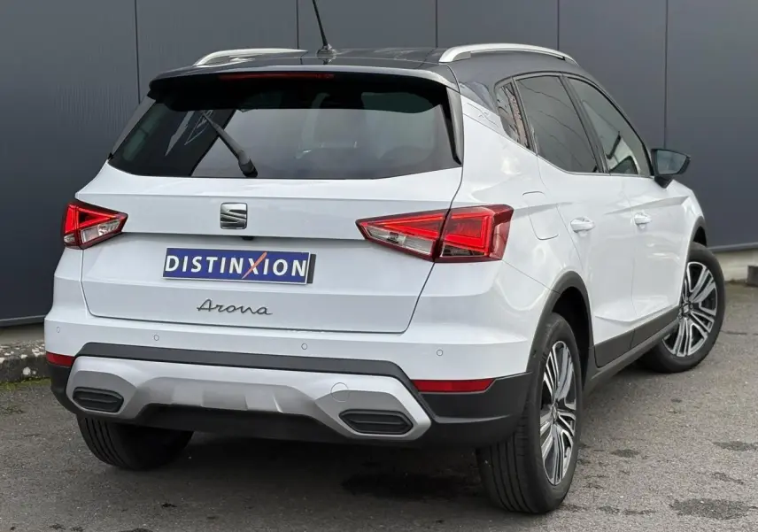 Vue 3/4 arrière droite d'un SEAT Arona blanc Nevada avec toit noir et feux arrière LED triangulaires.