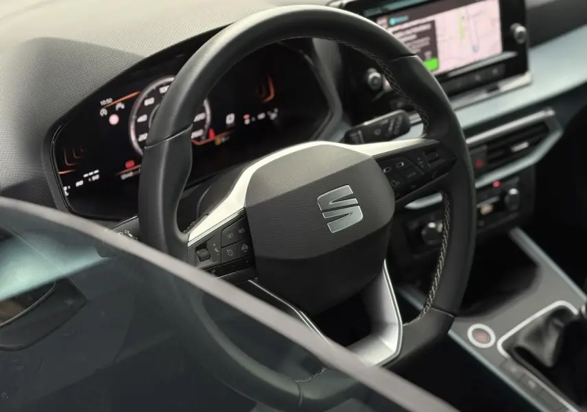 Volant cuir multifonction SEAT Arona TSI 115 Xpérience en gros plan avec tableau de bord numérique et console centrale.