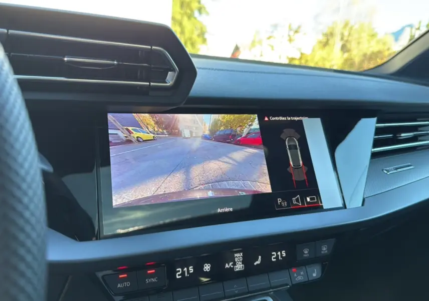 Vue intérieure du tableau de bord de l'Audi A3 TFSI 150 Hybrid S-Line 2025 avec écran caméra de recul et climatisation digitale.