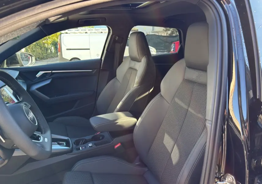 Intérieur de l'Audi A3 noir mythic vu côté gauche, sièges sport cuir tissu avec accoudoir central et volant cuir méplat.