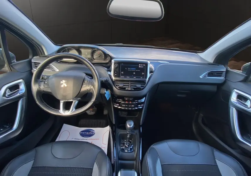 Vue intérieure avant du Peugeot 2008 gris platinium, montrant le tableau de bord, volant multifonction et console centrale avec écran tactile.