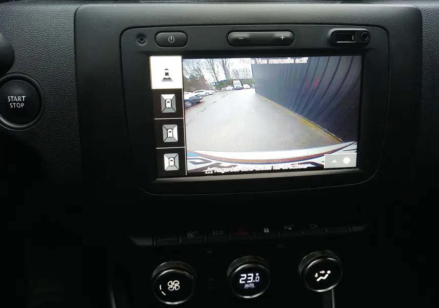 Vue intérieure du tableau de bord du Dacia Duster 2021, écran de caméra de recul avec affichage clair et commandes climatisation visibles.