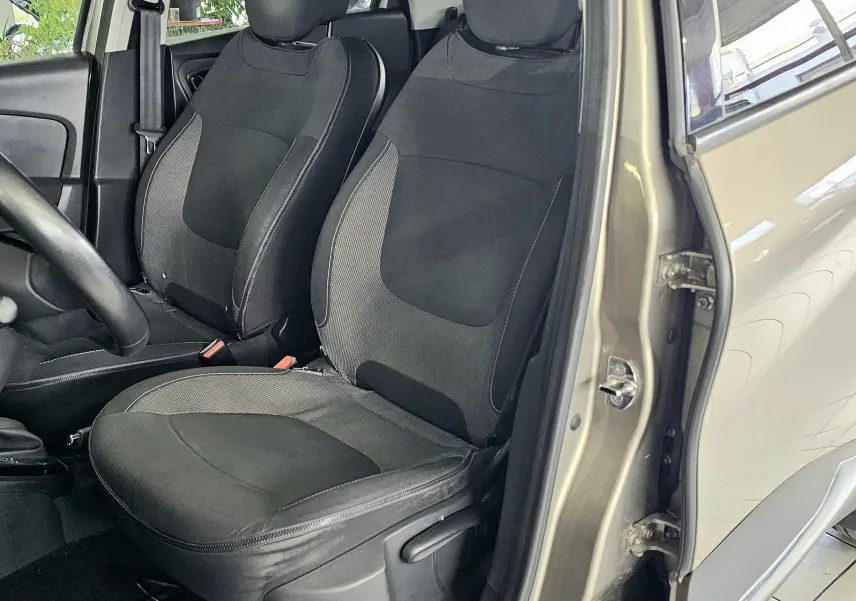 Vue intérieure côté conducteur du Renault Captur gris 2014, montrant les sièges avant et le volant.