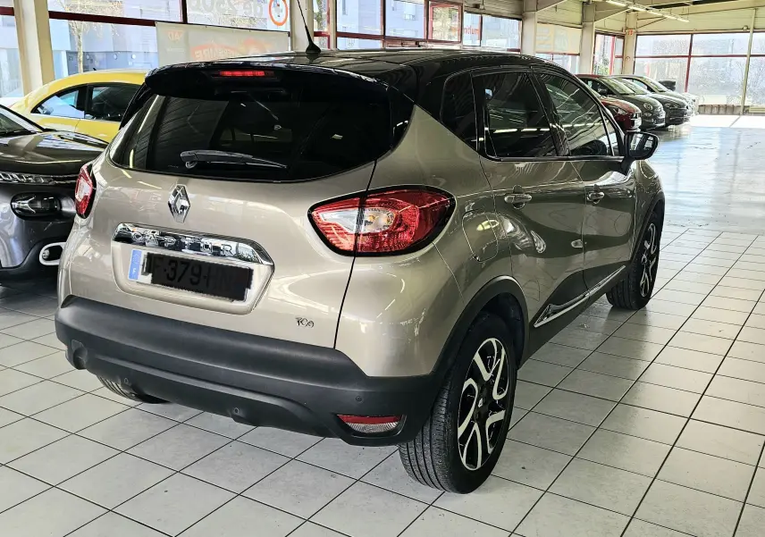 Vue 3/4 arrière droite du Renault Captur gris 2014 avec toit noir et jantes alliage distinctives.