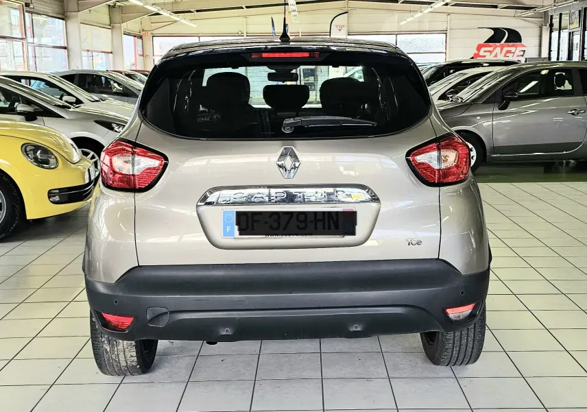 Vue arrière d'un Renault Captur gris 2014, avec feux arrière distinctifs et pare-chocs noir dans un showroom.