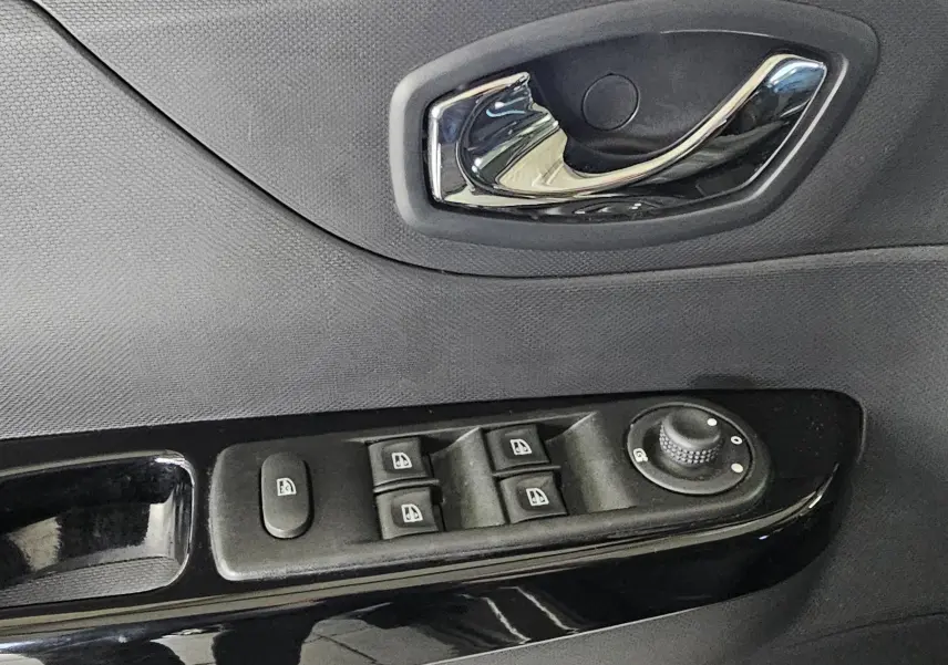 Gros plan sur la commande des vitres électriques et la poignée intérieure côté conducteur du Renault Captur gris 2014.
