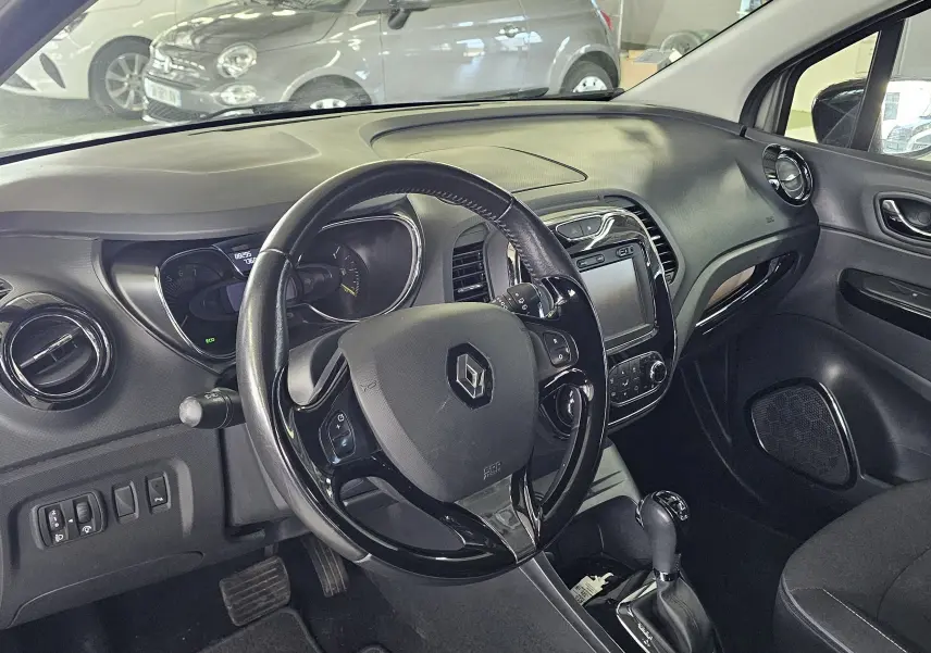 Vue intérieure côté conducteur du Renault Captur gris 2014, montrant le volant, tableau de bord et levier de boîte automatique.