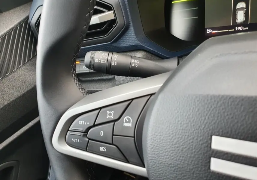 Gros plan sur les commandes au volant du Dacia Duster 2025, intérieur noir avec affichage numérique partiel.