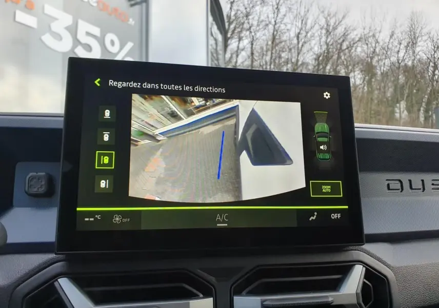 Écran central du Dacia Duster blanc glacier montrant la caméra de recul avec affichage multivues intérieur.
