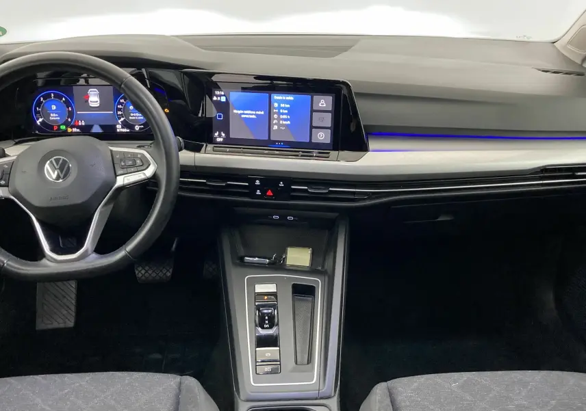 Vue intérieure frontale du tableau de bord de la Volkswagen Golf VIII gris reflex avec écran digital et éclairage bleu.