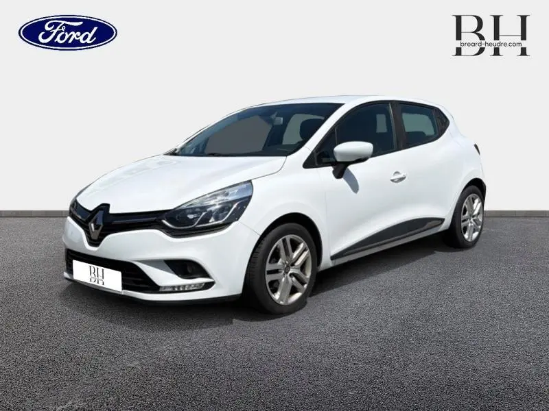 Renault Clio blanc vue 3/4 avant droit, avec jantes alliage et détails noirs sur les bas de caisse.