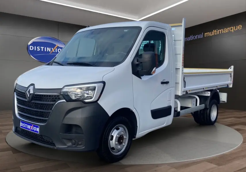 Renault Master blanc en 3/4 avant droit, benne arrière ouverte, calandre noire et jantes acier visibles.
