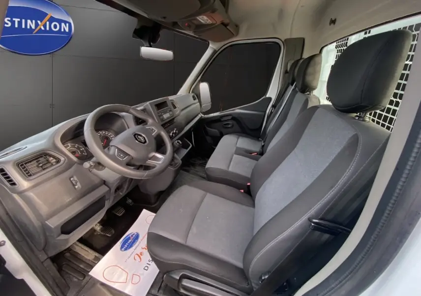 Vue intérieure côté conducteur du Renault Master 2024 blanc, montrant le tableau de bord et les sièges gris.