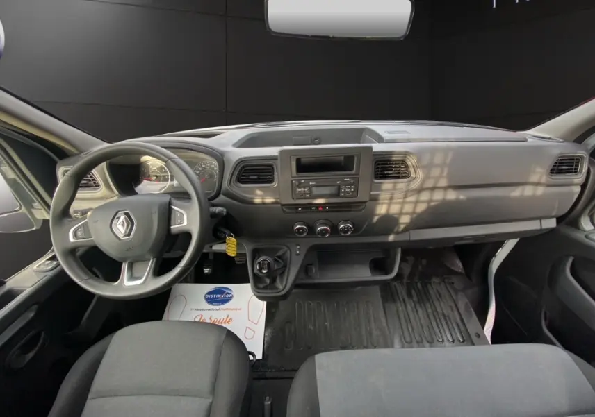 Vue intérieure avant du Renault Master 2024 blanc, tableau de bord simple avec volant multifonction et boîte manuelle.