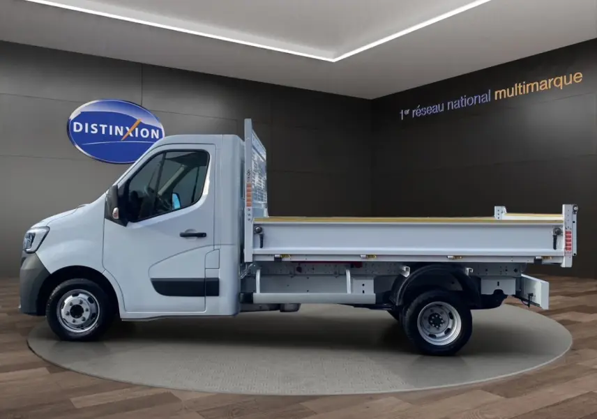 Profil droit d’un Renault Master blanc 2024 avec benne arrière, présenté en intérieur sur fond sombre.