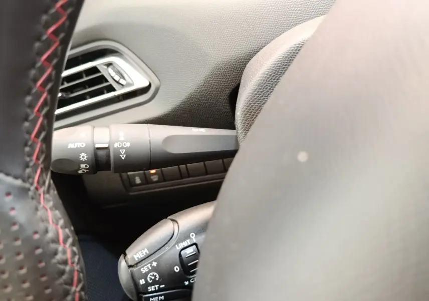 Gros plan sur le volant cuir noir avec coutures rouges et commandes de régulateur de vitesse sur Peugeot 308 GT Line 2016.