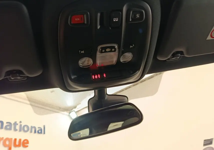 Vue en contre-plongée du plafonnier et du rétroviseur intérieur d'une Peugeot 308 noire de 2016.