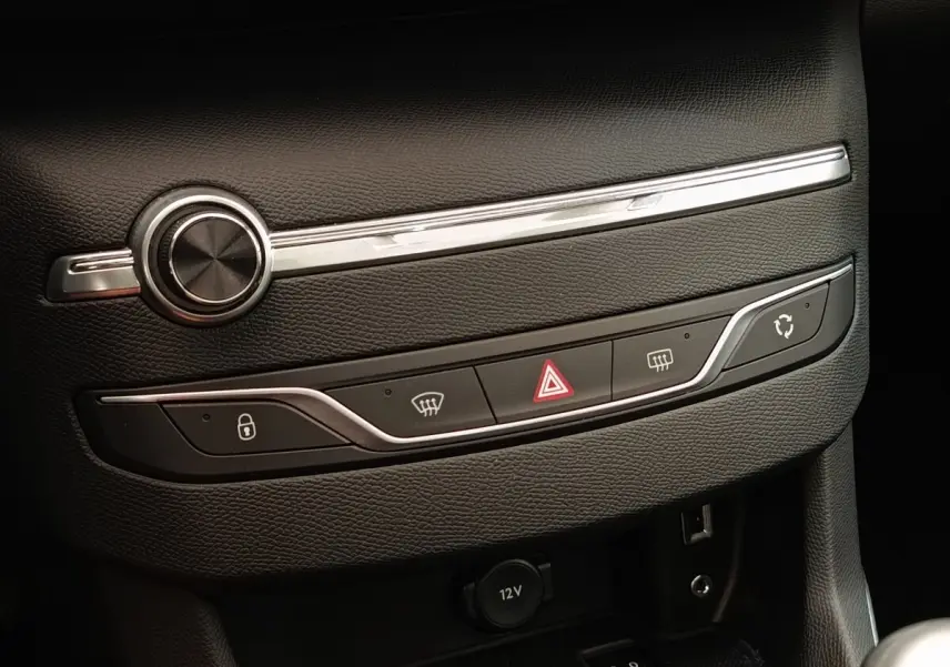 Vue rapprochée de la console centrale noire de la Peugeot 308 GT Line 2016 avec commandes de verrouillage, hazard et climatisation.