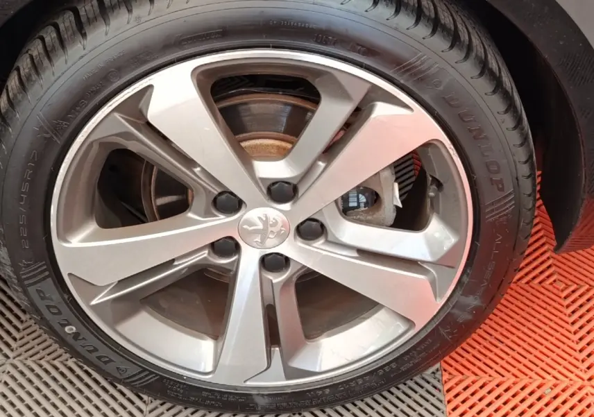 Gros plan sur la jante alliage argentée et le pneu Dunlop d'une Peugeot 308 noire, vue côté droit.