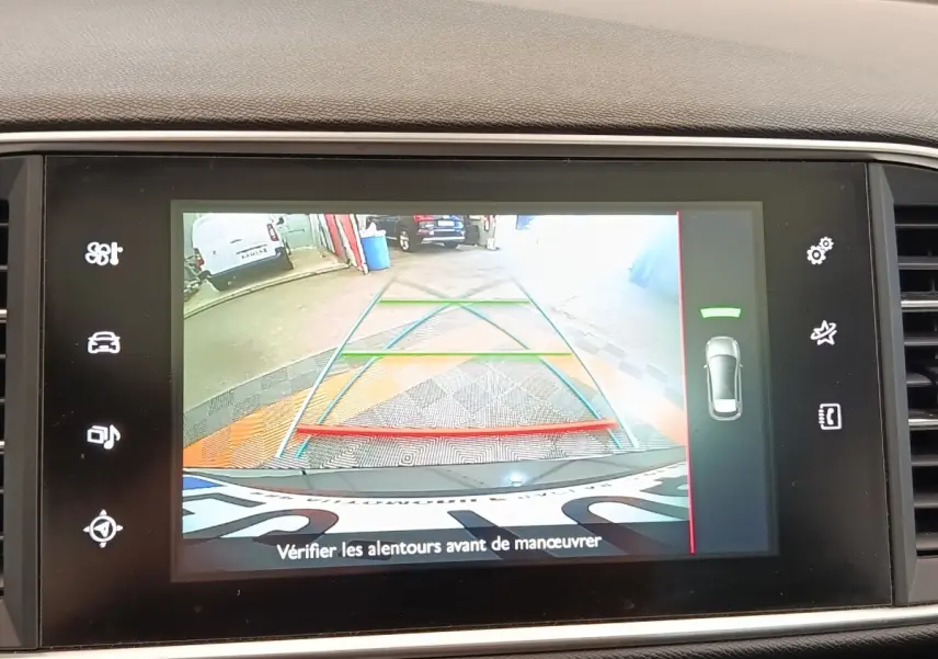 Écran tactile intérieur montrant la caméra de recul avec lignes de guidage colorées sur Peugeot 308 noir, vue arrière.
