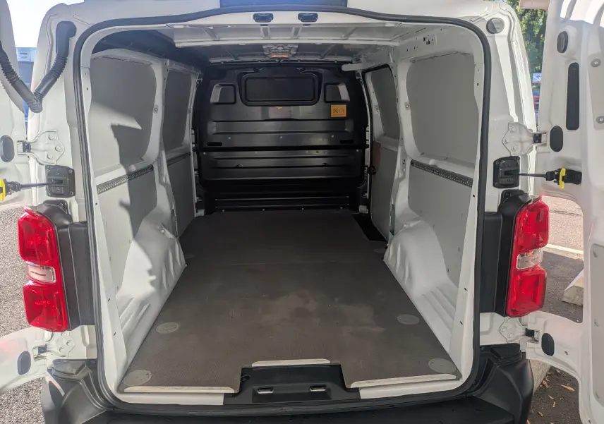 Vue arrière du fourgon blanc FIAT Scudo XL 2025 avec portes ouvertes et espace de chargement vide et modulable.