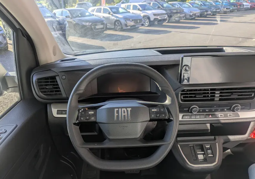Vue intérieure centrée sur le volant FIAT et le tableau de bord avec écran tactile large du Fiat Scudo Fourgon blanc.