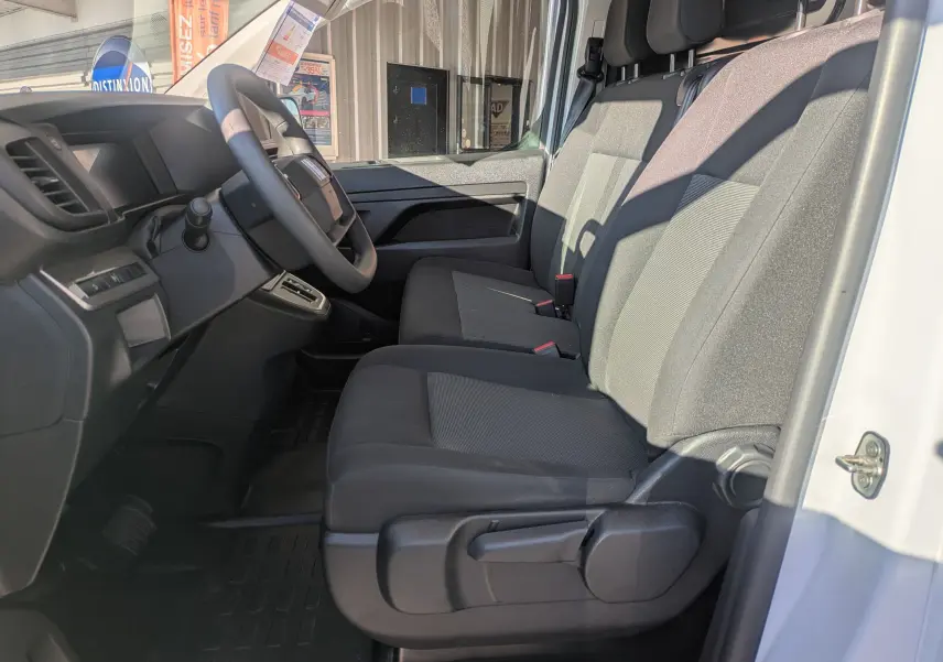 Vue intérieure côté conducteur du Fiat Scudo Fourgon blanc 2025, montrant la banquette modulable noire et le tableau de bord.