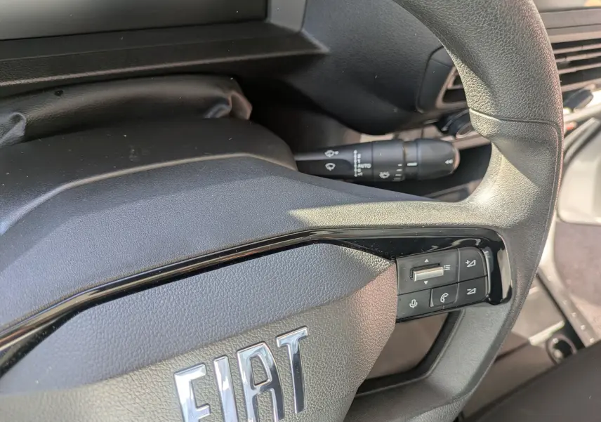 Gros plan sur le volant noir du Fiat Scudo Fourgon 2025 avec commandes intégrées et logo FIAT visible.