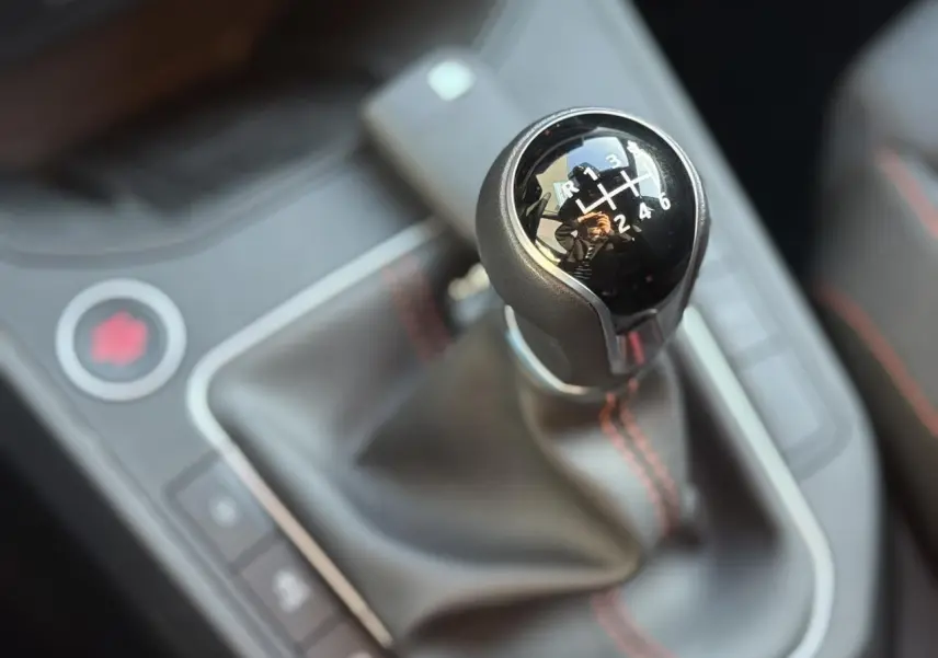 Le levier de vitesses manuel noir avec surpiqûres rouges de la SEAT IBIZA TSI 115 FR 2025 en gros plan intérieur.