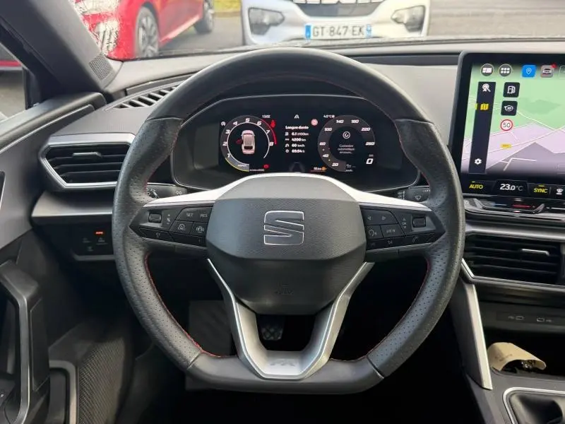 Vue intérieure centrée sur le volant perforé de la SEAT LEON ST 2025 avec tableau de bord numérique et écran tactile.