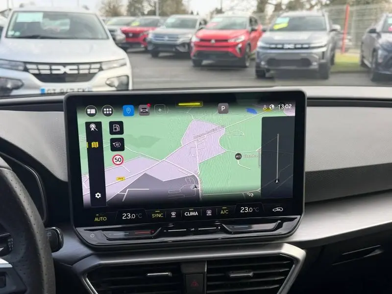 Vue intérieure du tableau de bord du SEAT LEON ST 2025 avec écran tactile affichant la navigation, volant partiel visible.