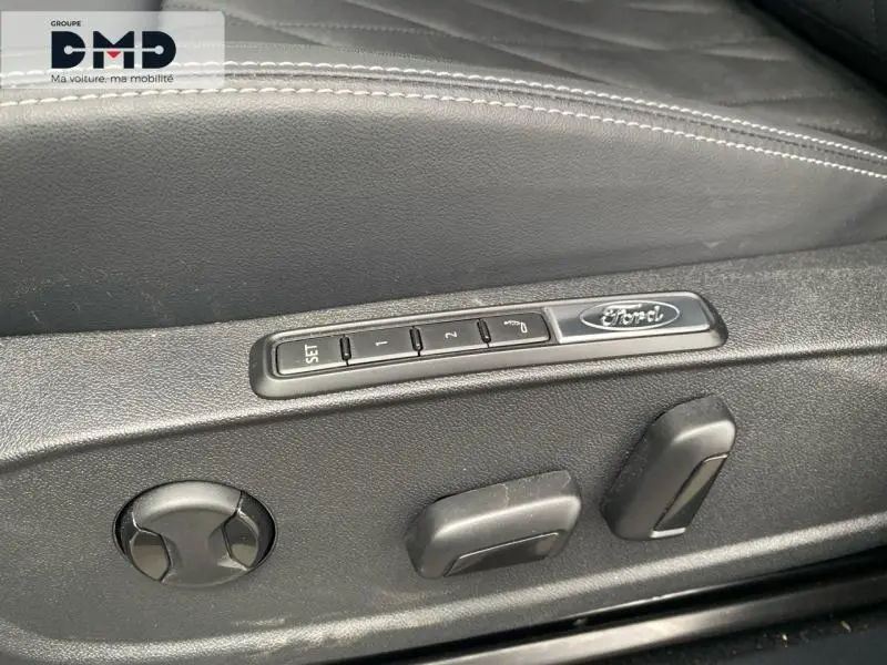 Gros plan sur les commandes de réglage électrique du siège conducteur noir avec logo Ford sur un Ford Explorer gris Magnetic.