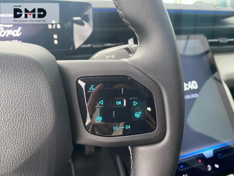 Vue rapprochée du bouton multifonction à droite du volant noir du Ford Explorer 2025, avec écran tactile en arrière-plan.