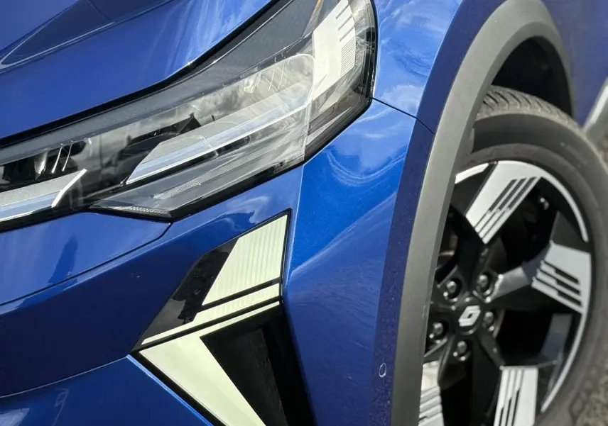 Gros plan sur l'avant droit bleu Iron du Renault SYMBIOZ 2025, avec phare LED et jante 18 pouces Gravity.